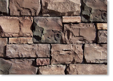 Close-up of a brown stone masonry wall with irregular rectangular stones and visible mortar.
