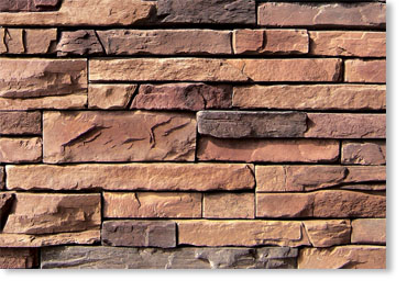 Close-up of a brown stacked stone wall with rectangular bricks in earthy tones.