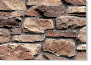 Close-up of a rustic stone wall made of irregular brown stones with light mortar.