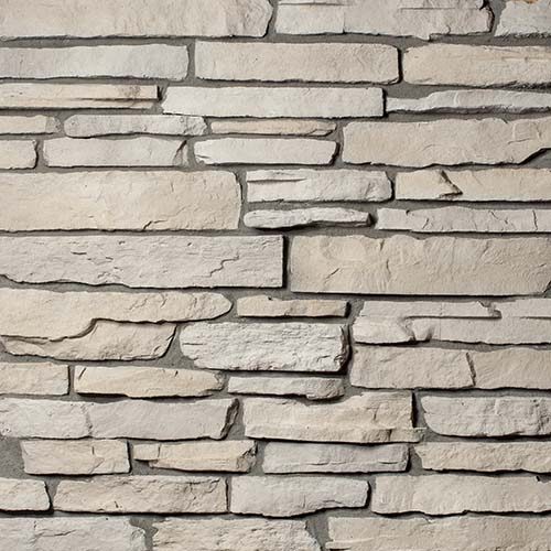 Beige stacked stone wall with irregular rectangular stones.
