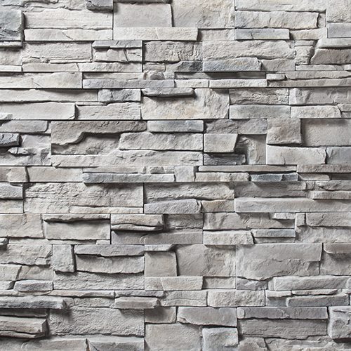 Grey stacked stone wall with irregular rectangular stones and subtle shadows.