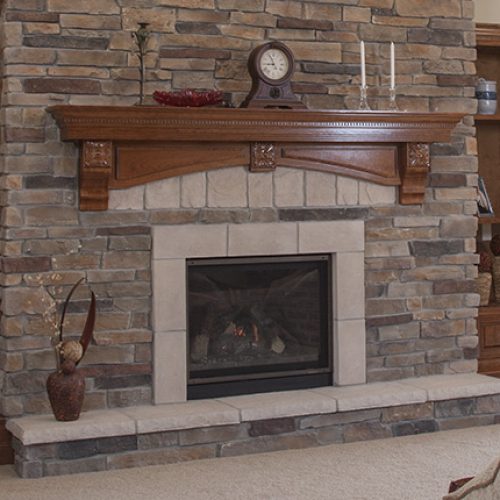 Stone fireplace with a wooden mantel, clock, and candleholders on top; beige hearth and stacked stone surround.