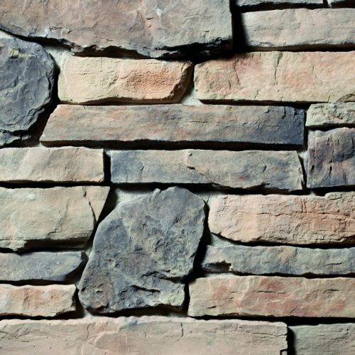 Close-up of a stacked stone wall with flat, rectangular stones in gray and tan tones.