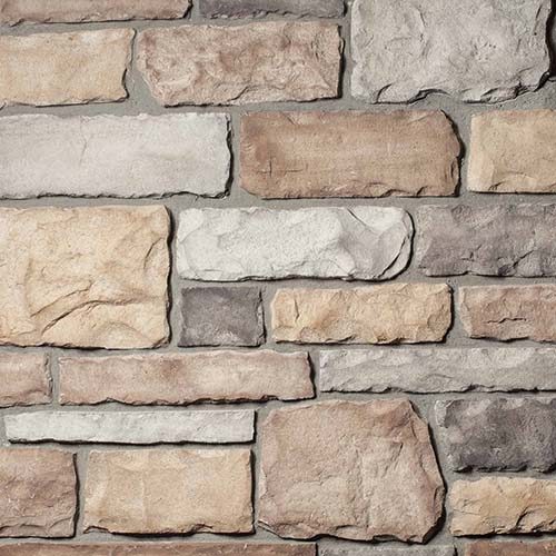 Close-up of a beige and gray stone veneer wall with irregular rectangular blocks.