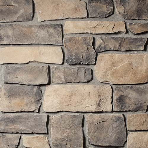 Close-up of a stacked stone wall with tan, gray, and brown rectangular stones.