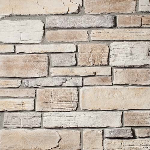 Close-up of a beige and gray stacked stone wall, showing rectangular blocks and subtle mortar lines as a decorative surface.